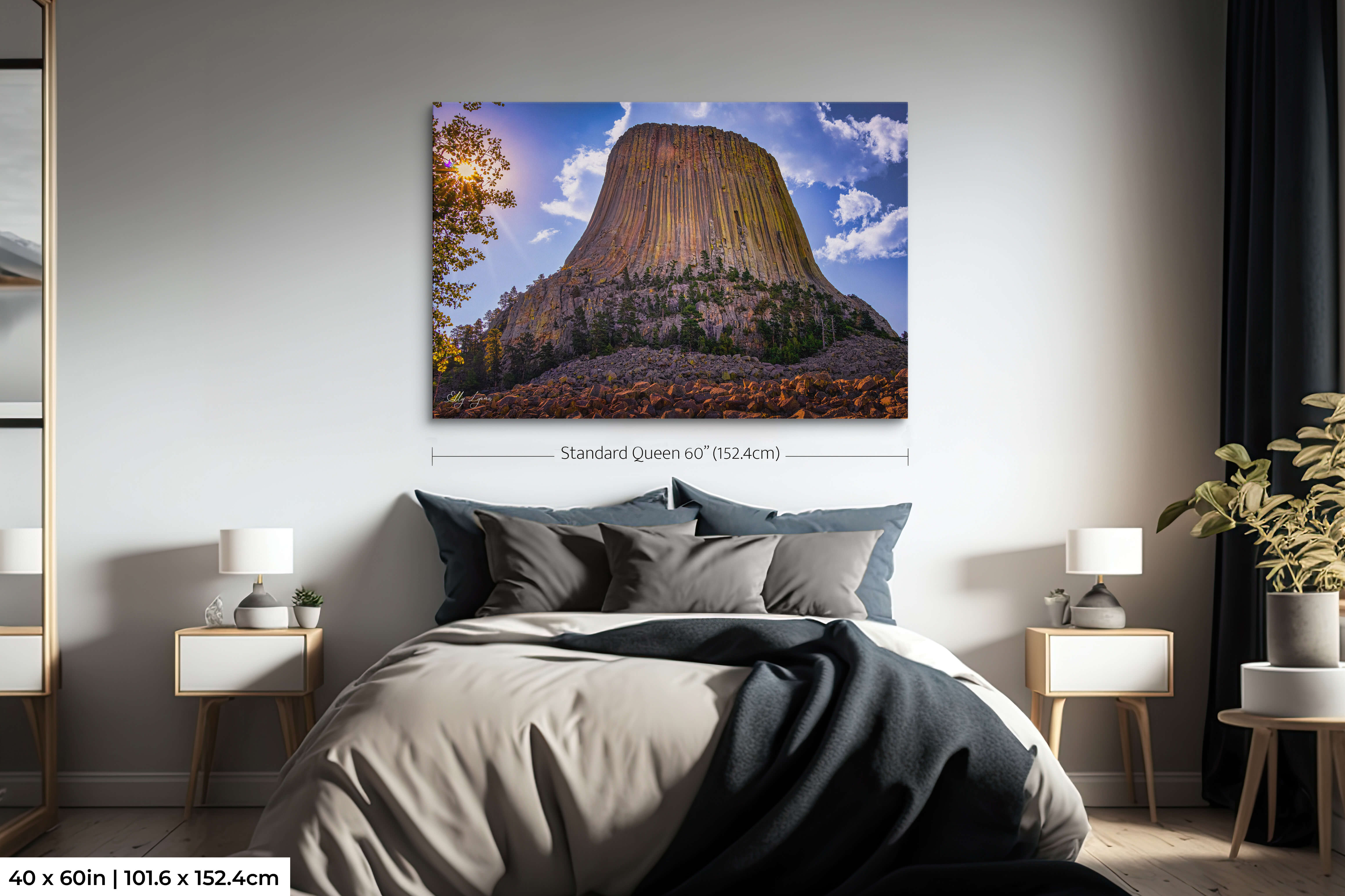 Single-panel 40x60 Devil’s Tower fine art print with glowing sunburst hung above a queen bed in a cozy, light-filled bedroom space.